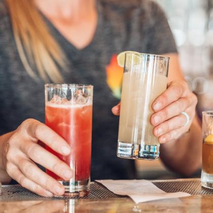 A bartender picks up two drinks to bring to a customer