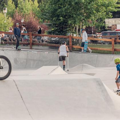 People of all ages riding around in a skatepark