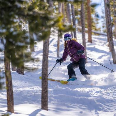 woman skiing through trees