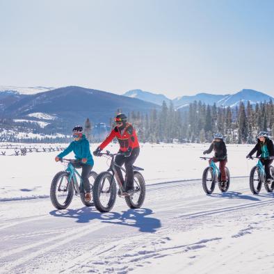 A group of friends fat biking through scenic winter trails