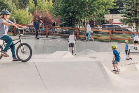 People of all ages riding around in a skatepark