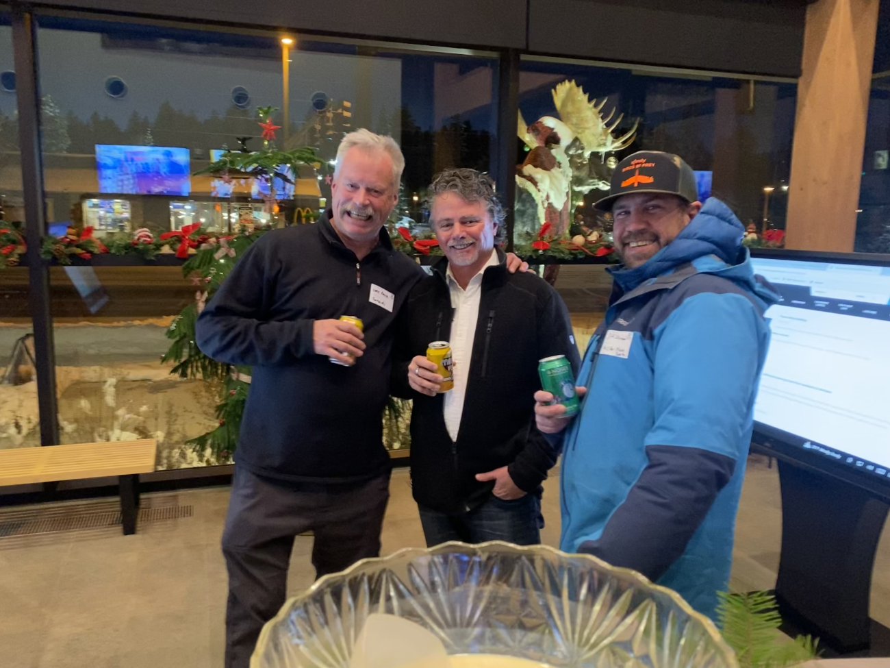 three men holding drinks in jackets