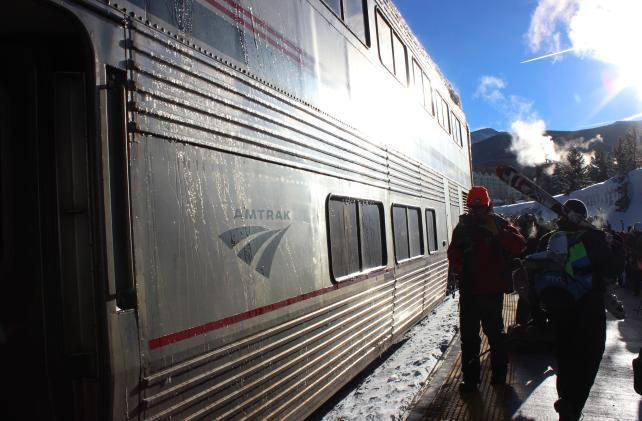 train with people walking by it 